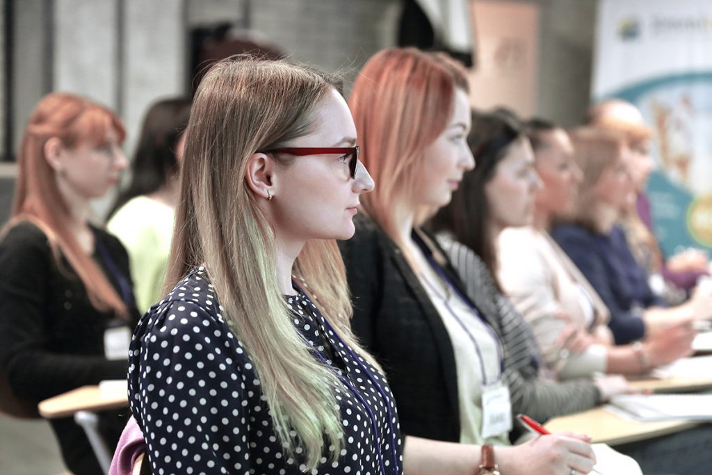 Group of two rows of people listening and taking notes during a training session.